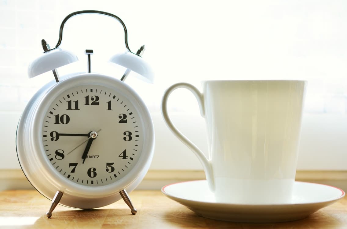 Alarm clock next to a coffee cup on a windowsill