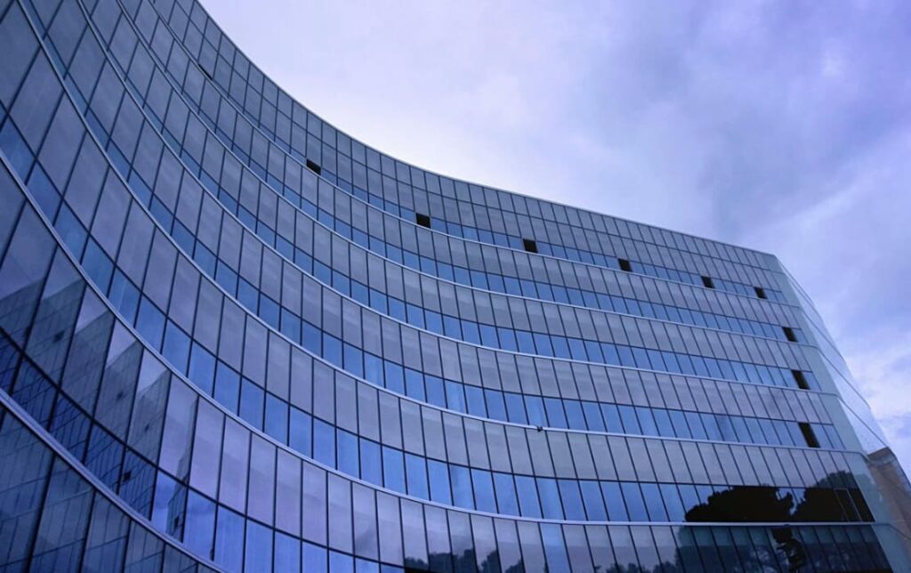 Curved glass office building under a cloudy sky