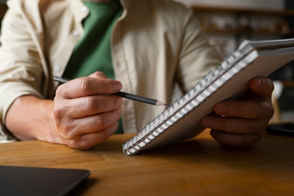 A man holds a notebook and pencil in his hands