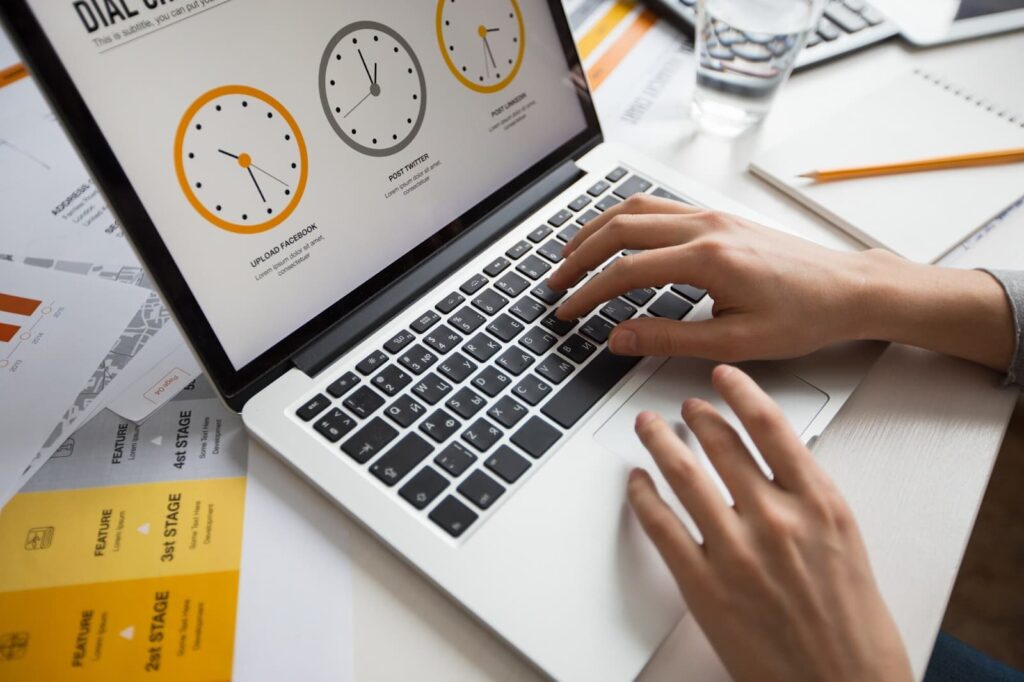 A girl's hands on the keyboard of a laptop on the screen of which a clock is depicted