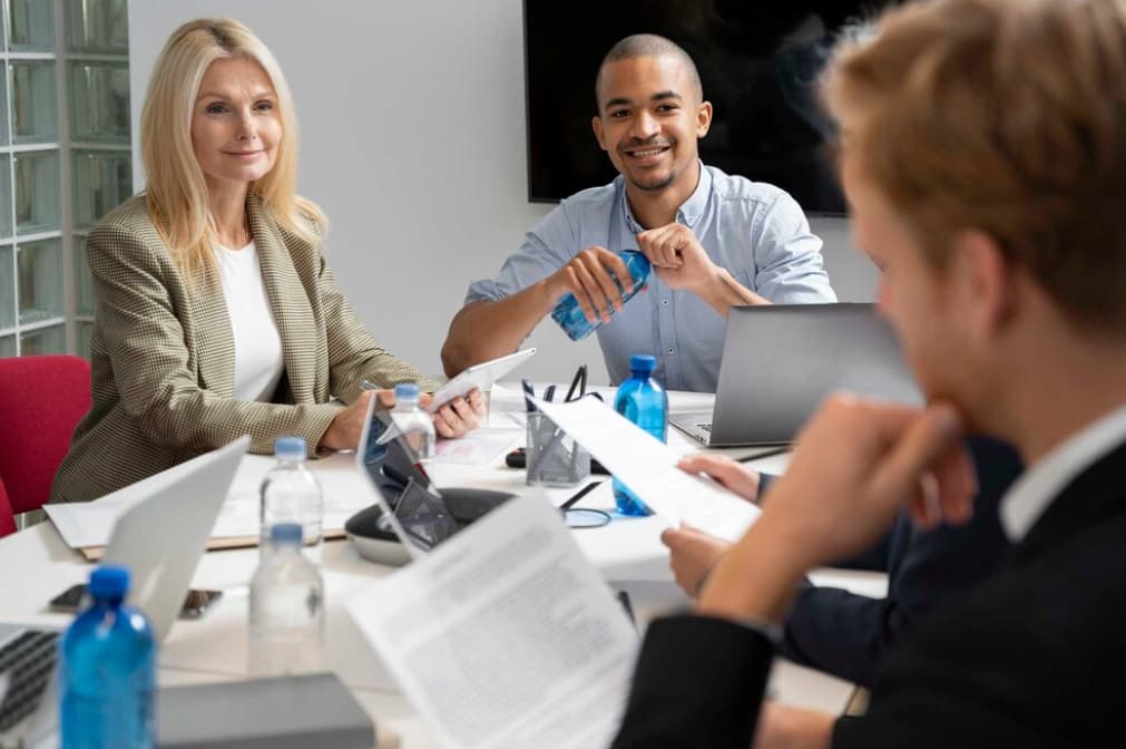 Three professionals in a meeting with laptops