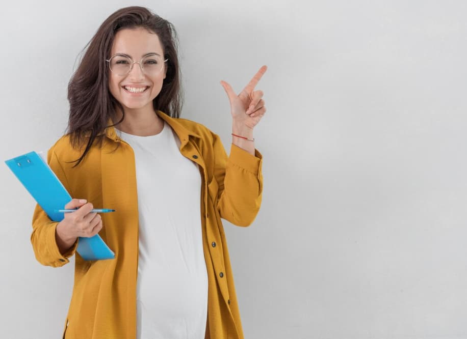 a smiling woman in white t-shirt standing near white wall and holding blue sheets