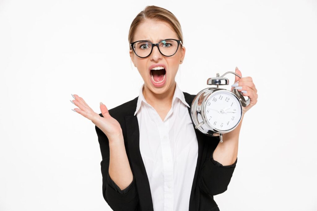 Screaming businesswoman in glasses running late while holding alarm clock and over white wall