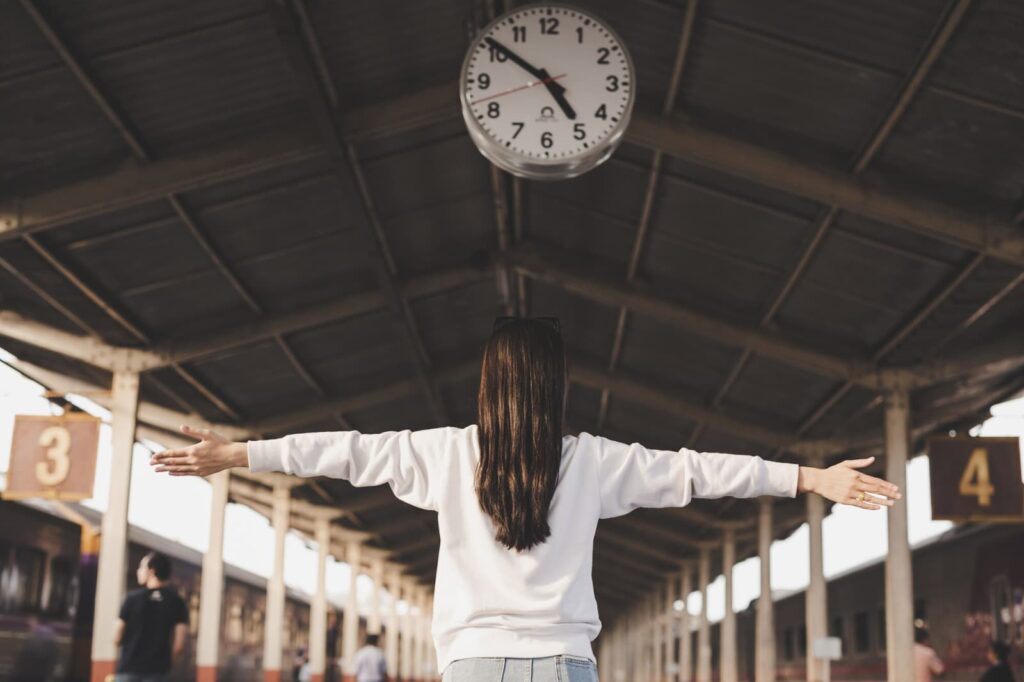 A woman stands in front of a clock