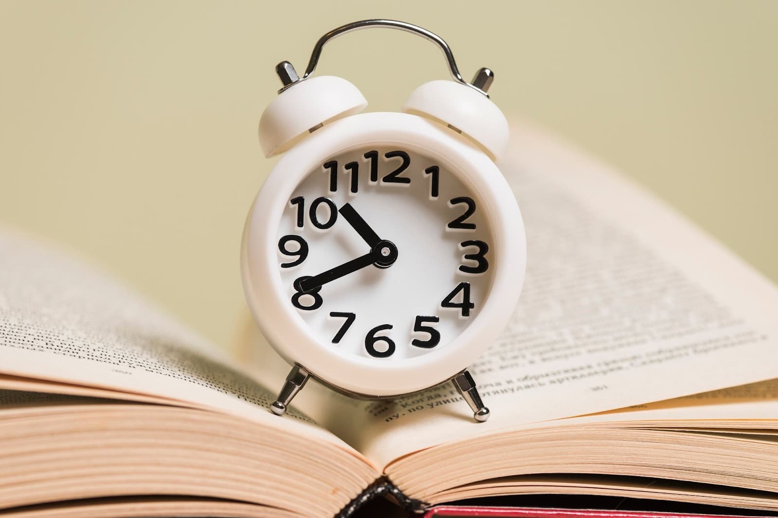 Close-up of white alarm clock on an open book