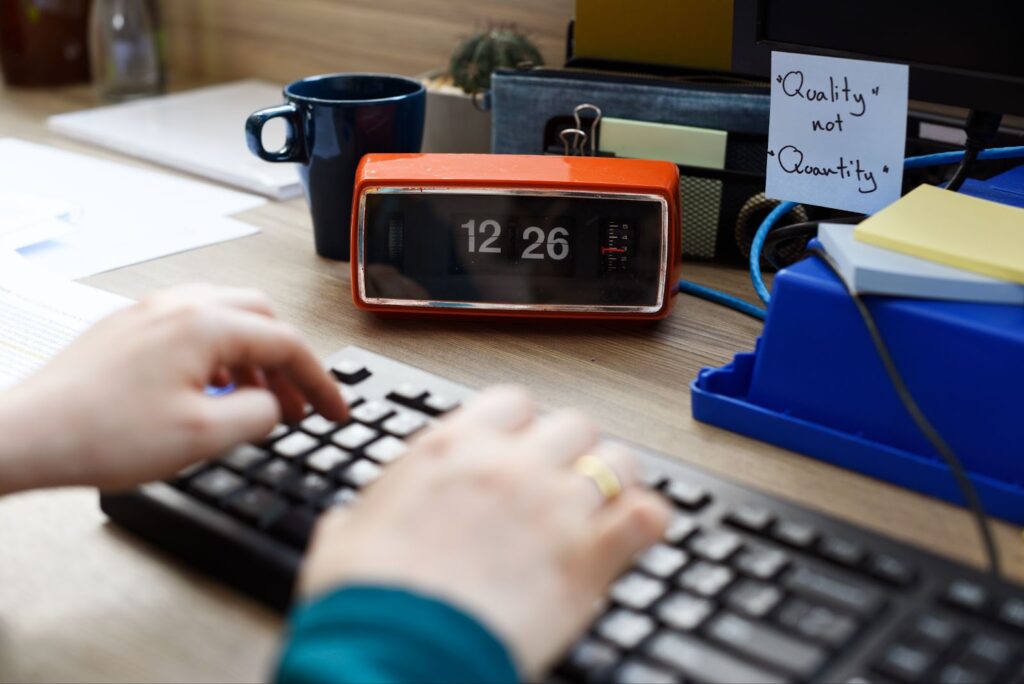 Close up of man typing on keyboard near clock