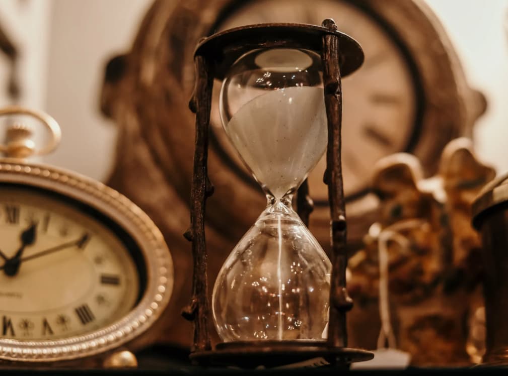 An hourglass on a stand with sunset in the background