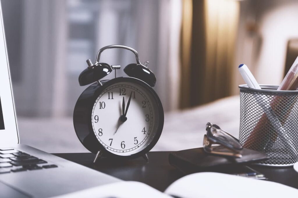 Alarm clock on a desk near a laptop