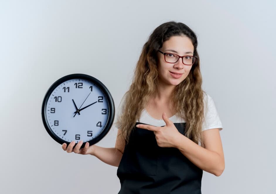 Woman holding a large clock and pointing to it