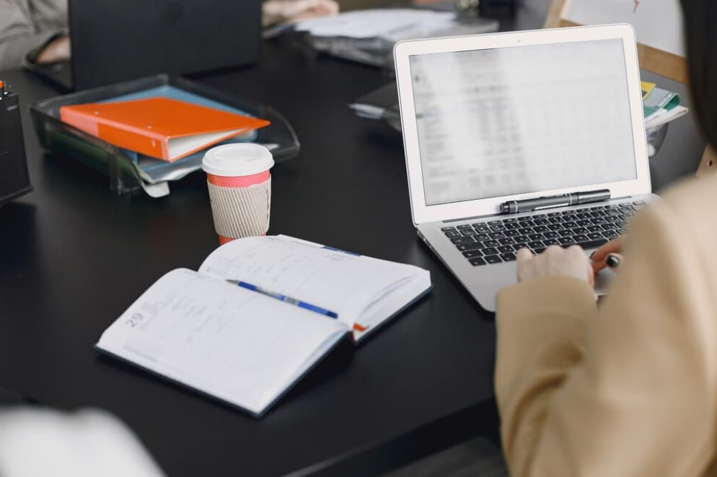 Person at desk with open laptop and notepad